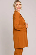 Woman wearing rust-colored long blazer and matching pants, stylish boutique outfit