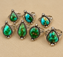 Ornate Turquoise Rings on Beige Fabric.png